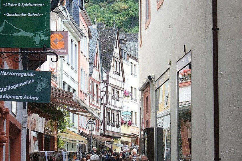A narrow street lined with traditional buildings, a sign for a local market, and a view of a mountain in the background. 5