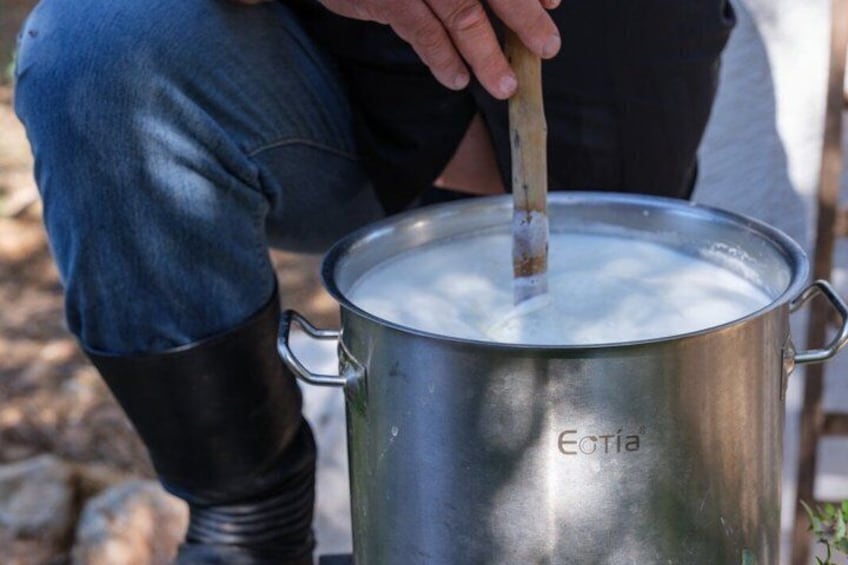 A person stirring a pot labeled 'Eotía' outdoors. 2
