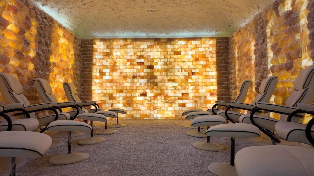 A room with stone walls, a mosaic wall, and several chairs. 2