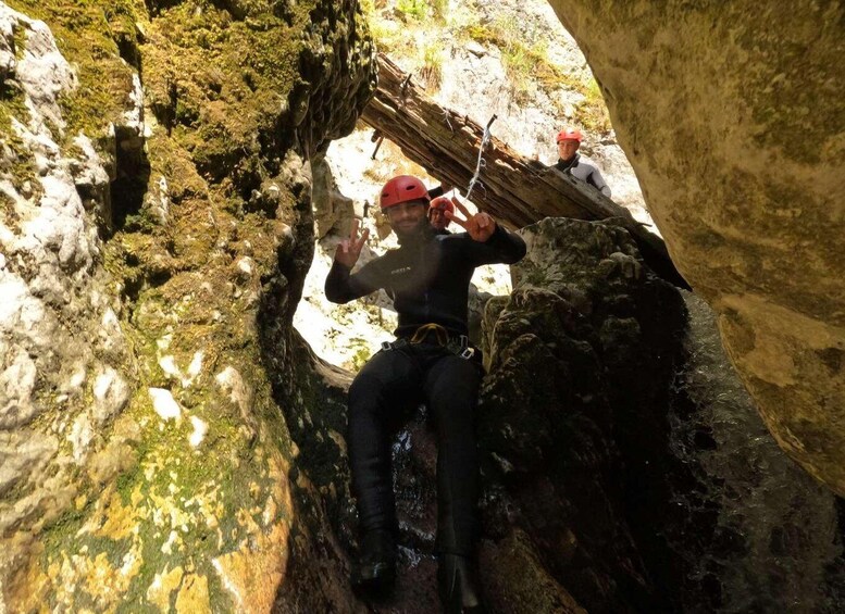 A person rappelling down a rocky cliff with moss-covered surfaces. 3