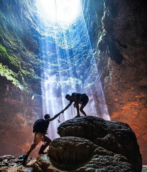 Two people climbing a rocky formation with a light source above. 4