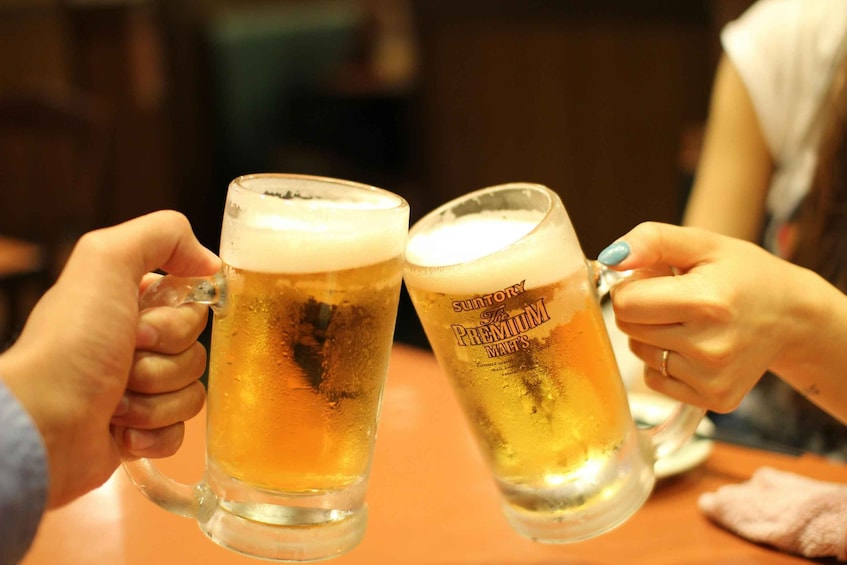 Two people holding beer mugs with foam, one labeled 'Suntory Premium Milds.' 1