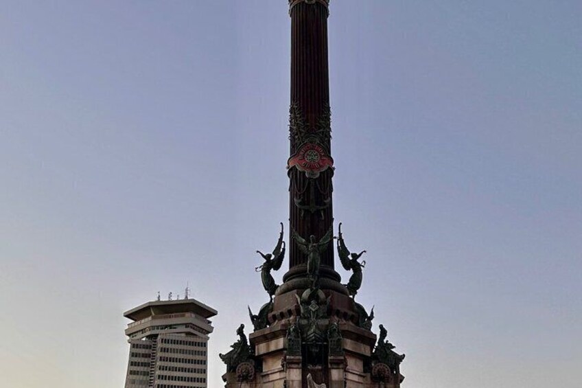 A tall, ornate monument with intricate designs and statues at its base, set against a clear sky. 5