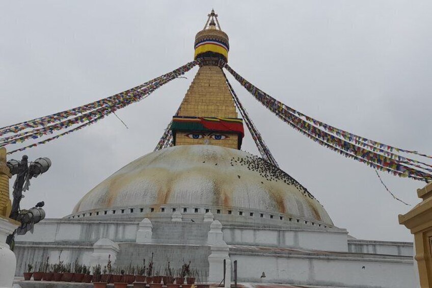 A large white stupa with a golden spire, surrounded by colorful prayer flags. 3