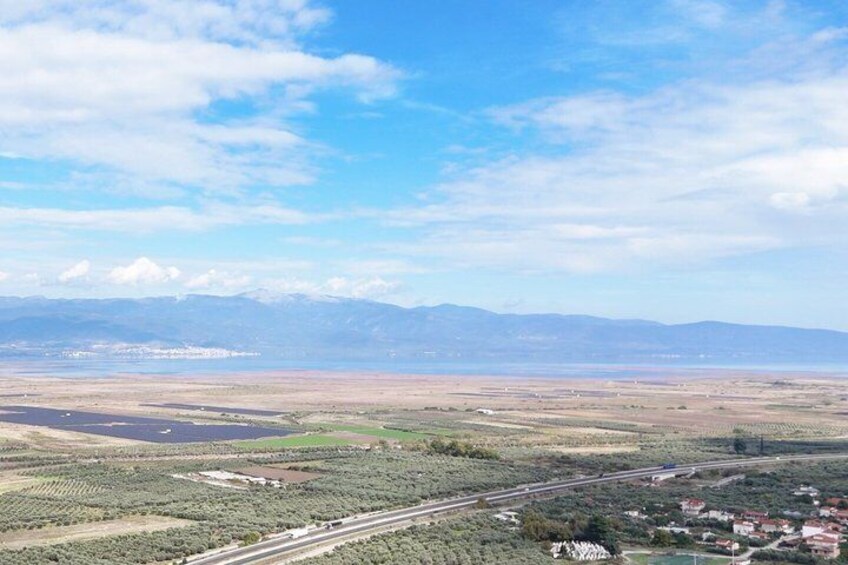 A vast landscape with a highway, fields, and distant mountains under a clear sky. 5