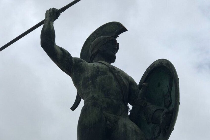 A bronze statue of a warrior holding a spear and shield. 1
