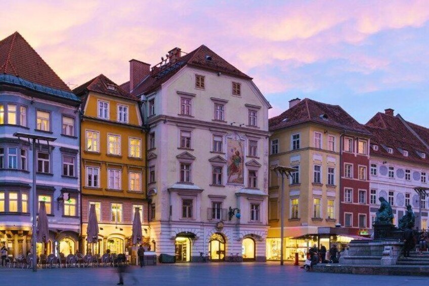 A historic European town square with colorful buildings and a fountain. 5