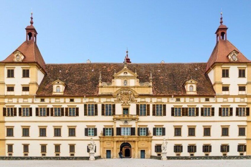 A large, historic building with a symmetrical facade, two prominent towers, and a central entrance with a decorative arch. 4