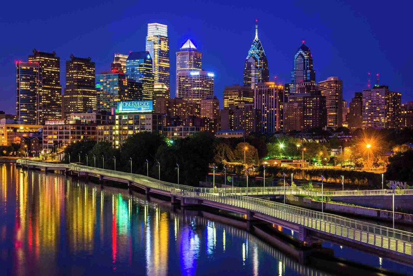 A nighttime city skyline with illuminated buildings and a bridge reflecting on the water. 3