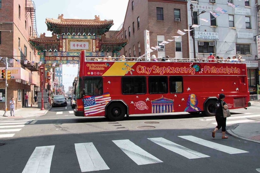 A red City Sightseeing bus with Philadelphia tour information, crossing an intersection with a pedestrian crossing. 4