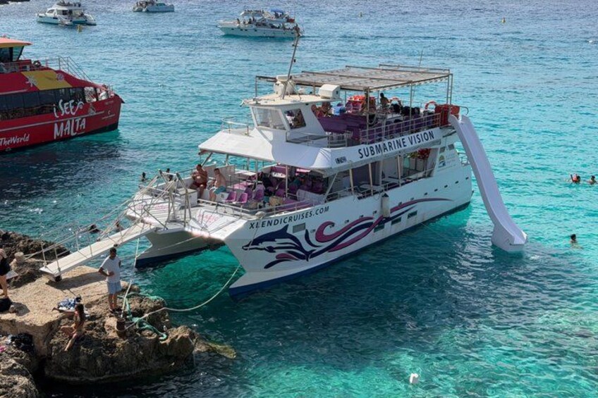 A white boat with 'SUBMARINE VISION' written on it docked at a pier with clear turquoise water. 1