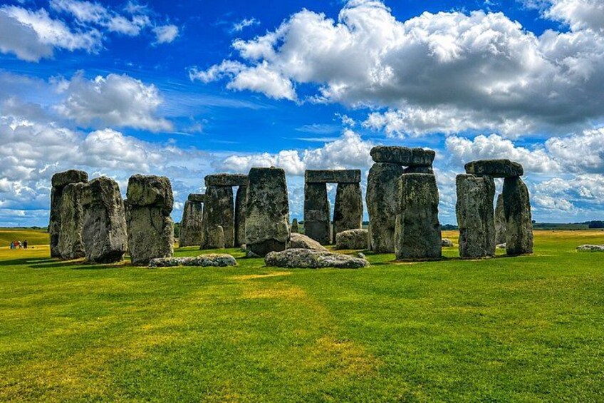 Stonehenge standing in a grassy field under a blue sky with clouds. 1