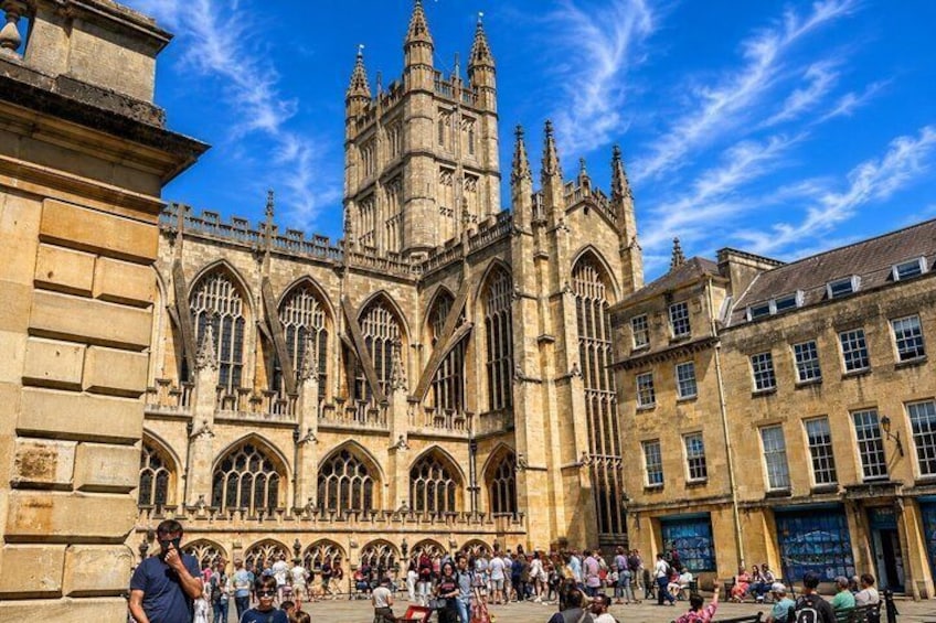 A historic cathedral with Gothic architecture, a crowd of people, and a clear blue sky. 4