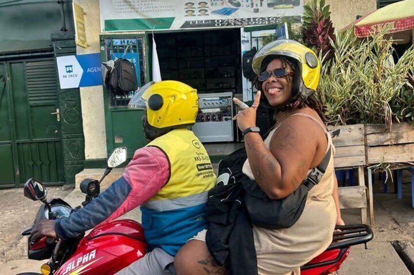 Two people on a motorcycle with helmets, a red motorcycle, and a shop in the background. 5