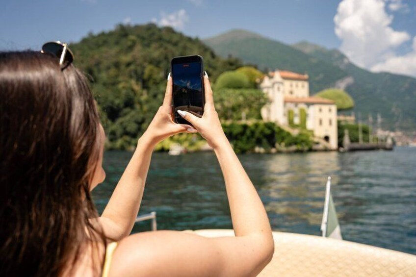 A person taking a photo of a lake with a building on the shore. 3