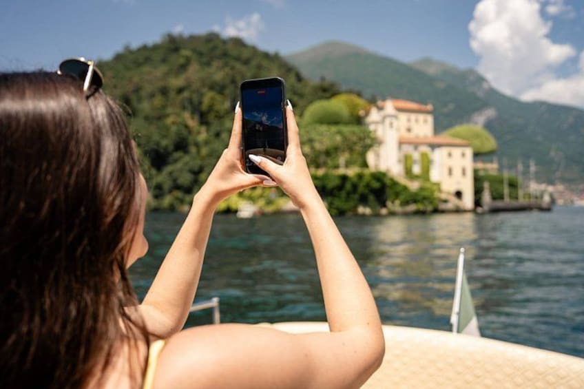 Une personne prend une photo d’un lac, avec un bâtiment situé sur une colline en arrière-plan. 2