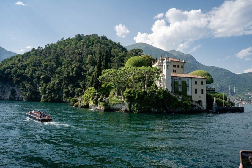 A boat on a lake, a castle on a hill, and mountains in the background. 4
