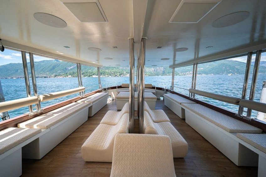 Un intérieur de bateau luxueux, doté de sièges confortables, de grandes fenêtres et d'un pont en bois. 4