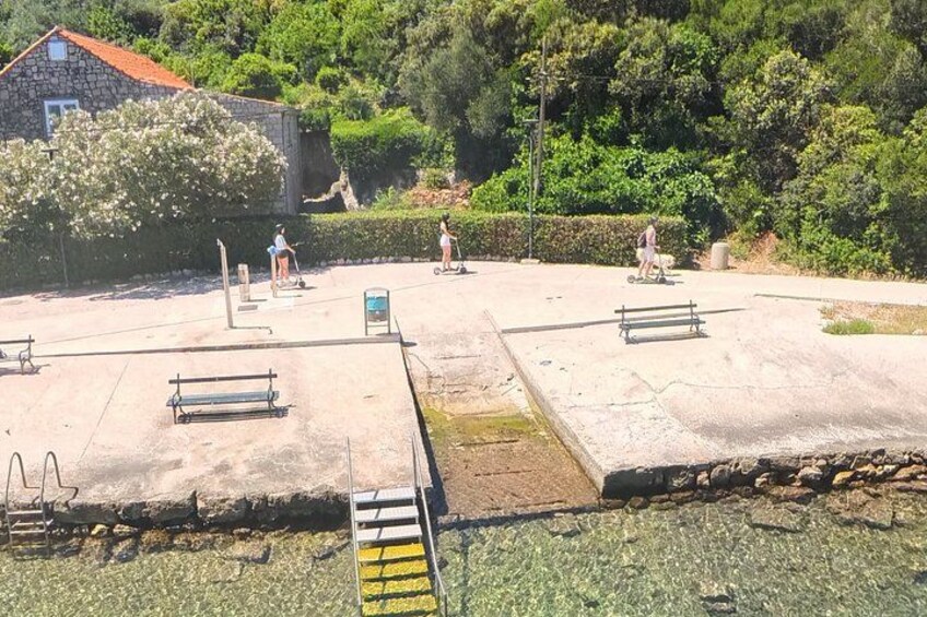 A concrete skate park with benches and a small building in the background. 2