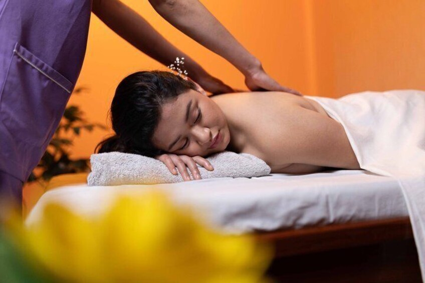 A person receiving a massage on a treatment table with a towel and a purple garment. 1