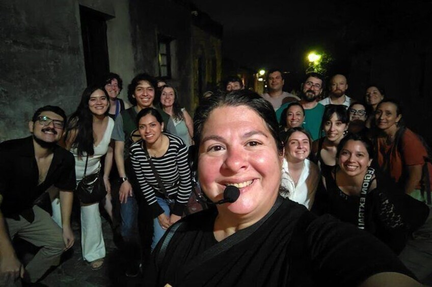 A group of people posing for a photo in an urban setting at night. 1