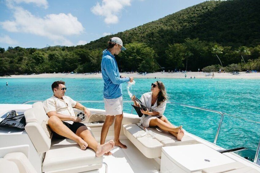 A boat on a turquoise sea with a beach and forested hills in the background. 5