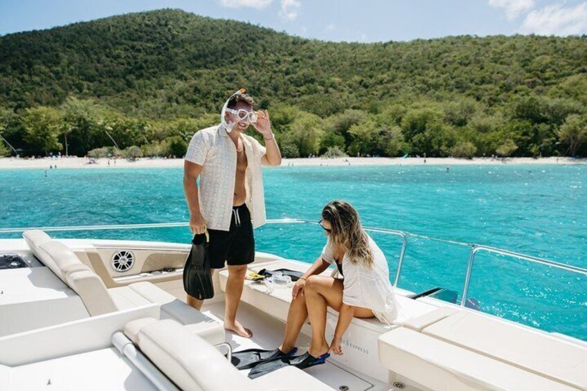 A boat on a turquoise sea with a forested hill in the background. 4