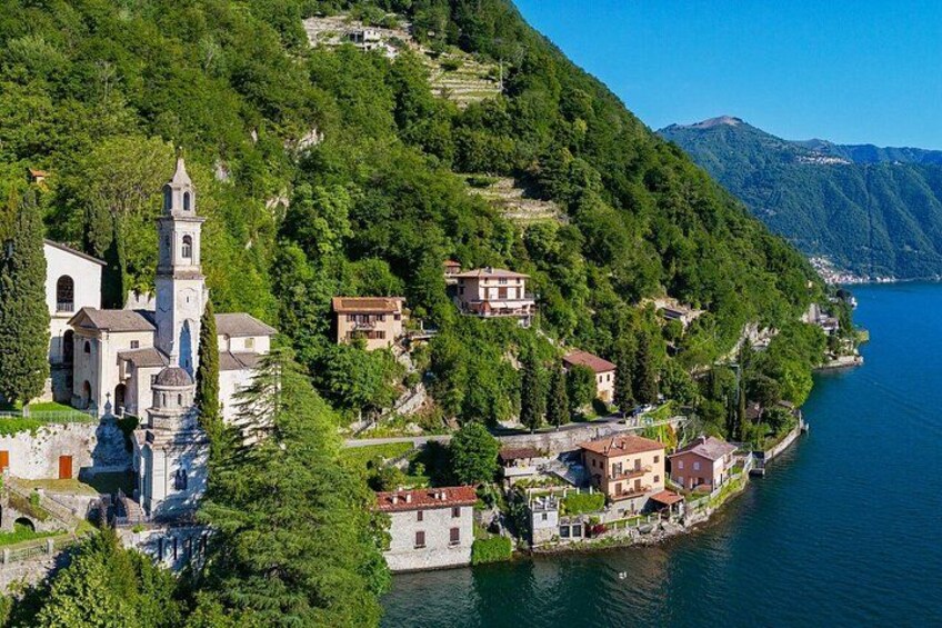 A coastal village with a prominent church, lush greenery, and a clear blue lake. 2