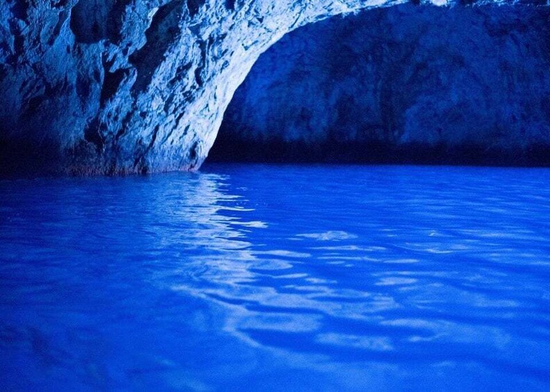 A cave entrance with water reflecting the blue light. 4
