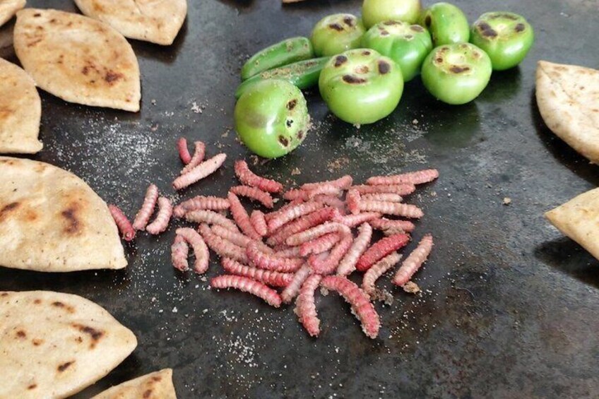 Tortillas, green tomatoes, and pink worms on a grill. 4