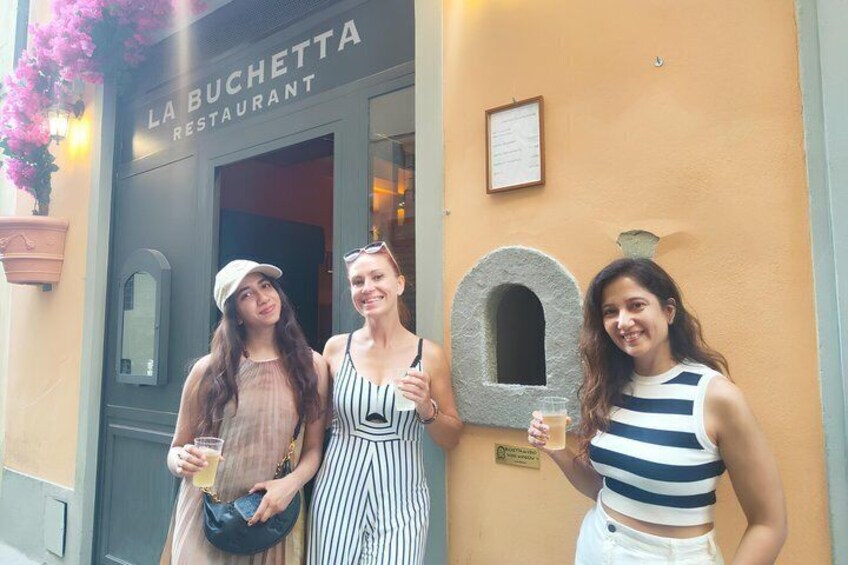 Three people standing in front of La Bucchetta Restaurant, holding drinks. 5