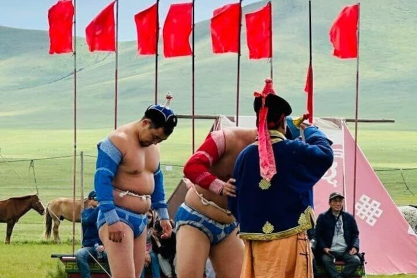 Two sumo wrestlers preparing for a match, with flags and a tent in the background. 5