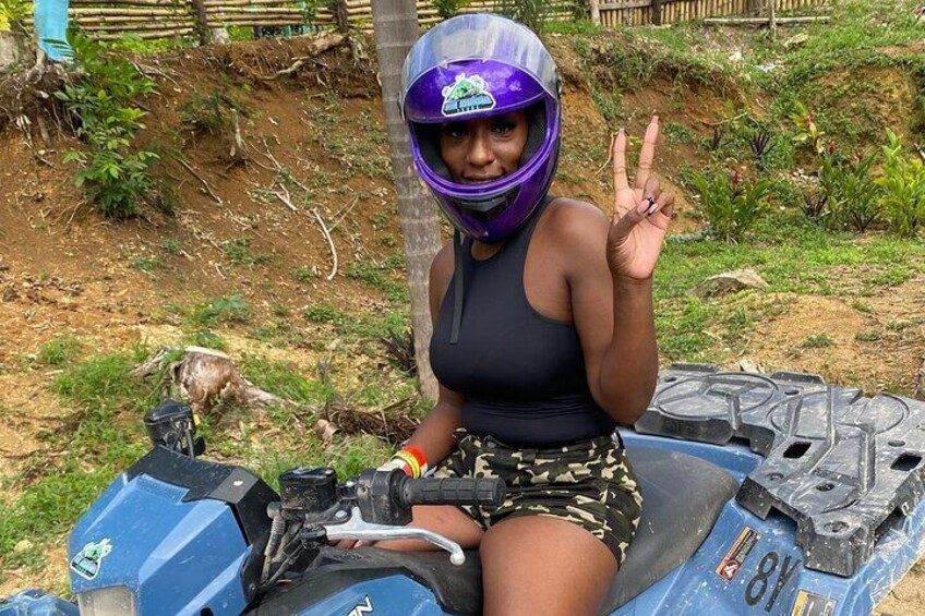 A person on a blue ATV with a number 81, wearing a helmet and making a peace sign. 1
