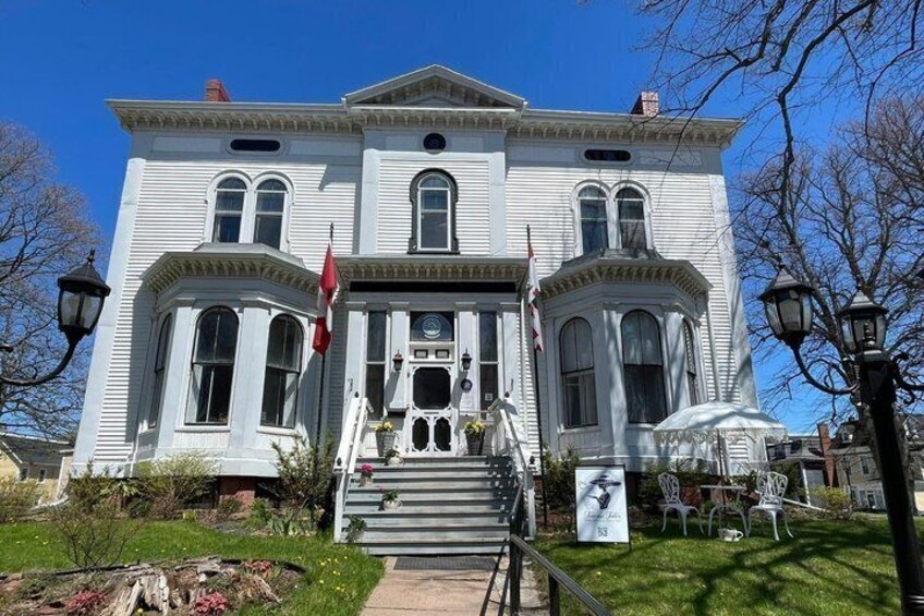 A white historic building with a flag, steps, and a garden. 4