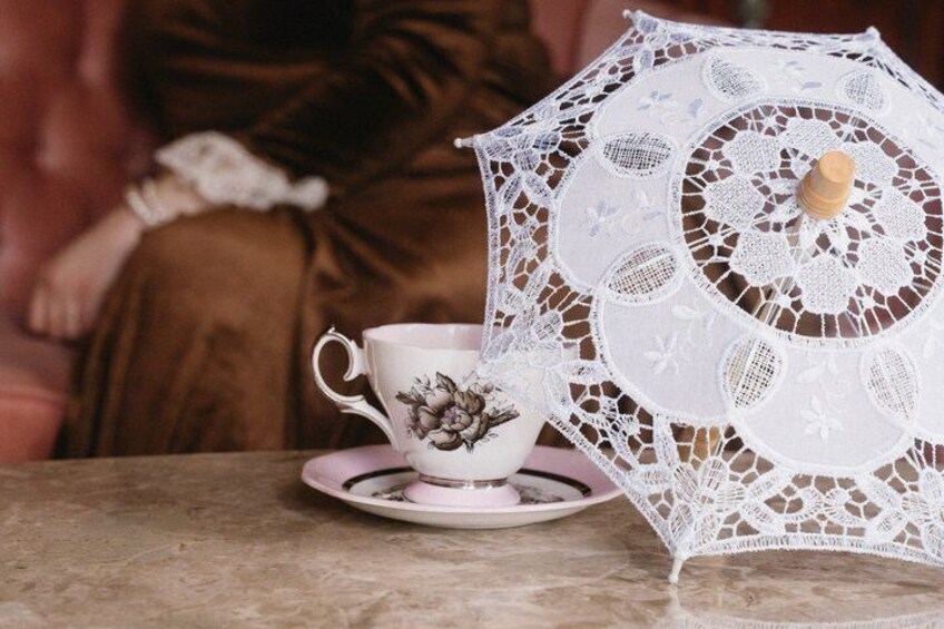 A lace umbrella, a teacup, and a saucer on a table. 1