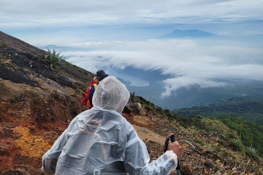 Two people hiking on a mountain trail with a view of clouds and distant mountains. 5