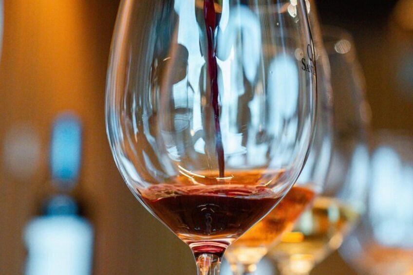A close-up of a wine glass with a red liquid being poured into it. 4