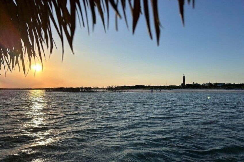 A sunset over a calm sea with a lighthouse in the distance. 3