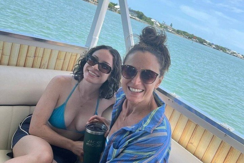 Two people on a boat with a body of water and distant land in the background. 5