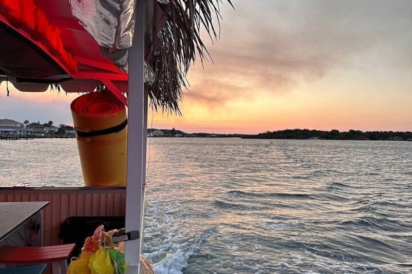 A boat with a red canopy and a yellow bucket, overlooking a sunset over the water. 2