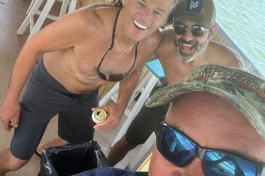 Two people in a boat, one holding a drink, and a black trash bin on the ground. 4