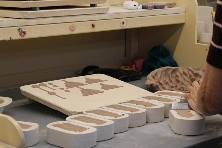 A person working with clay on a workbench, surrounded by various tools and materials. 5