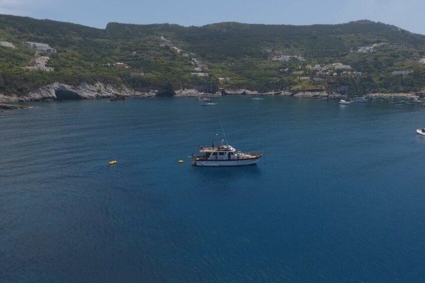 A boat on a calm sea with a hilly coastline in the background. 3