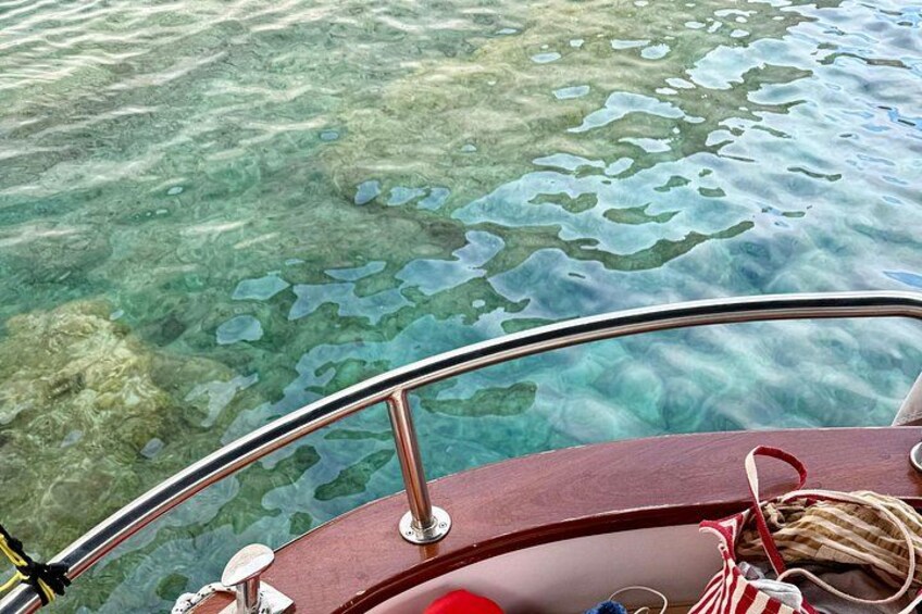A boat's bow with clear water and submerged rocks. 4