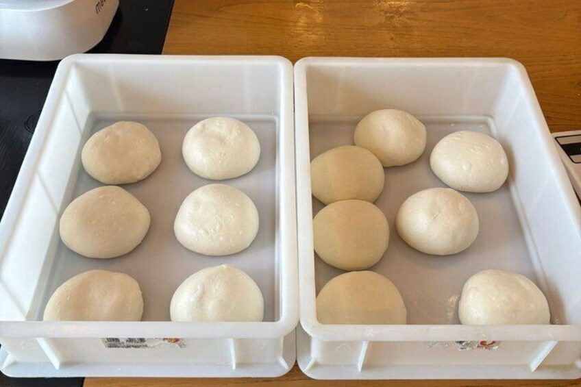 Two white plastic containers with round, uncooked dough balls. 3