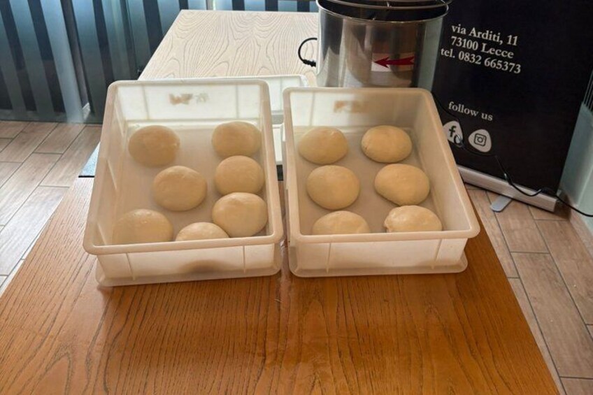 Two plastic containers with dough on a wooden table. 2
