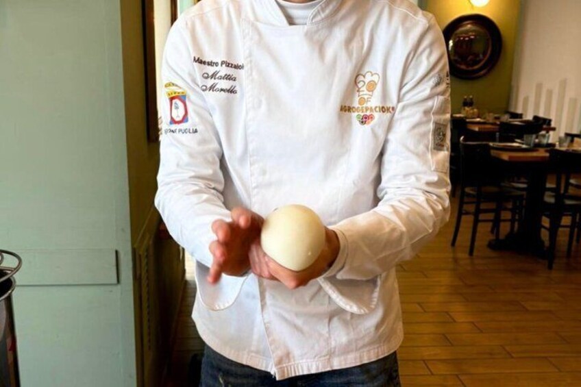 A person in a white chef's jacket holding a round object. 1