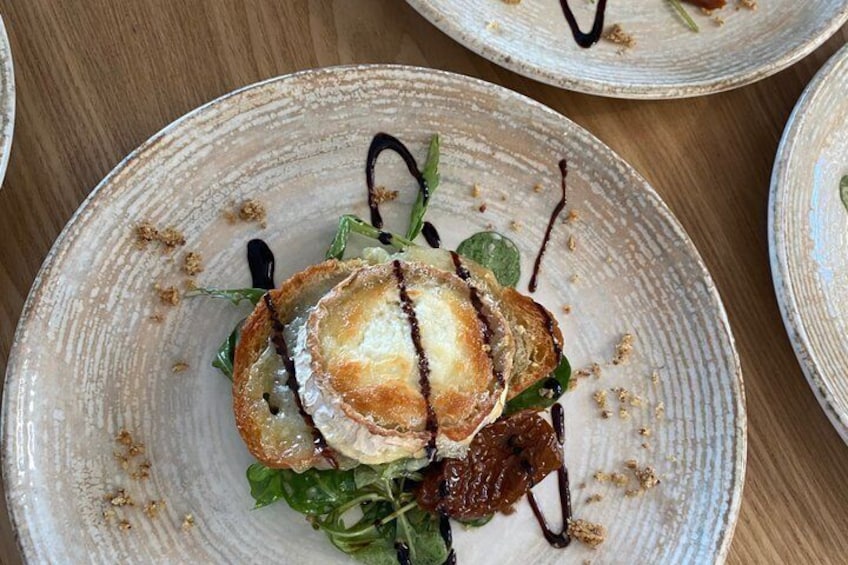A plate with a pastry, greens, and sauce. 1