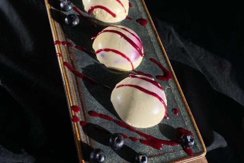 Three dessert balls with red syrup on a dark plate. 2