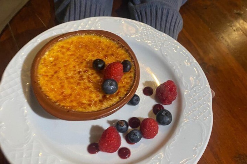 A dessert in a ramekin on a white plate with berries. 5